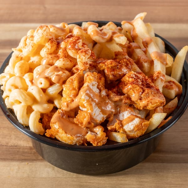 A black bowl filled with Chick-N-Guys fried chicken, fries, and mac and cheese, drizzled with sauce.